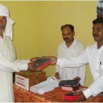 An elderly man gets his copy of the Bible from Rev. Pankaj Lal